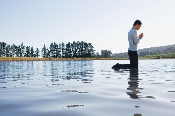 Man kneeling on water praying